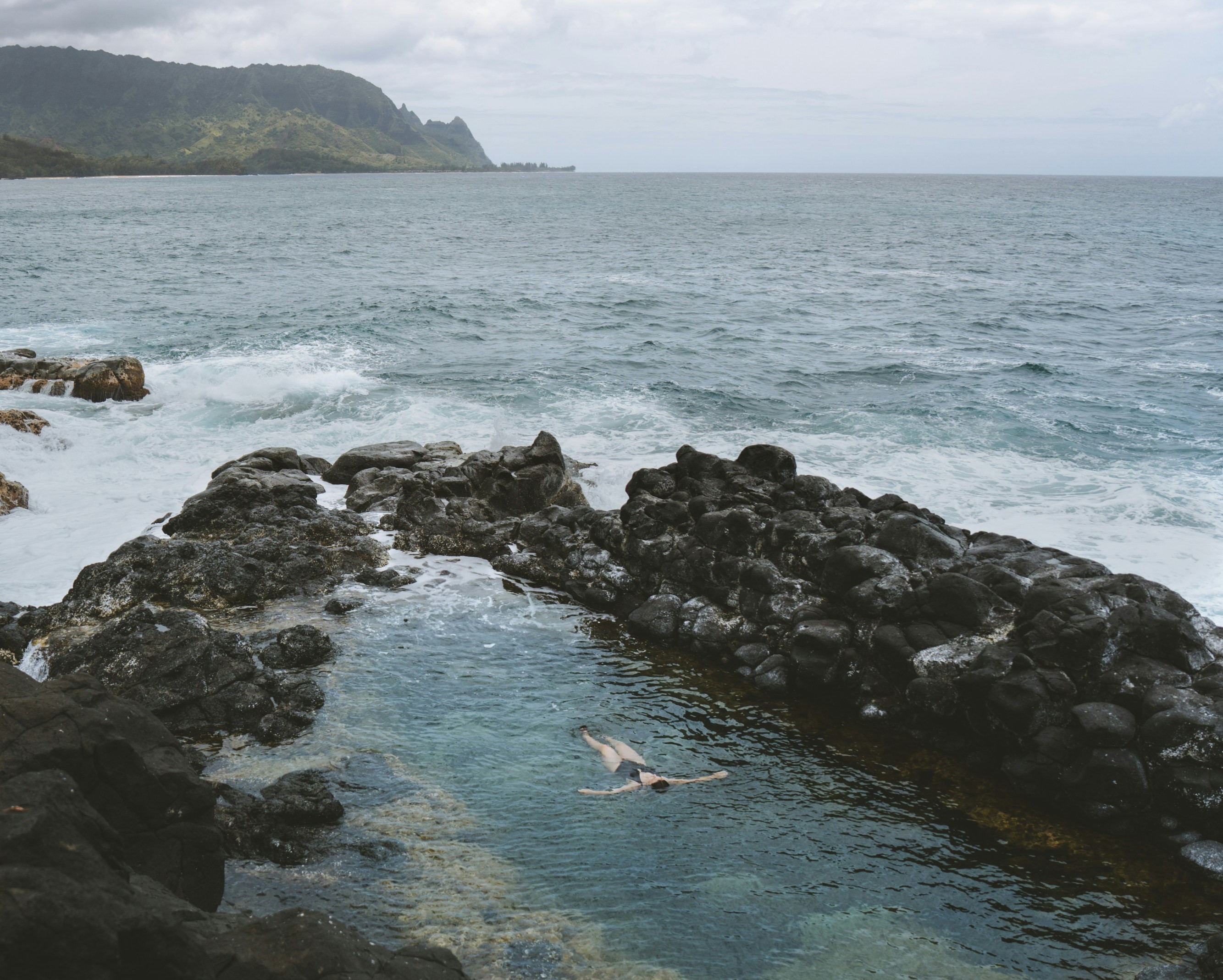 a body of water surrounded by rocks on a cloudy day